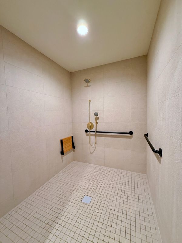 Accessible walk-in shower with small mosaic tile flooring installed at Church of Pickleball renovation in Chicago IL